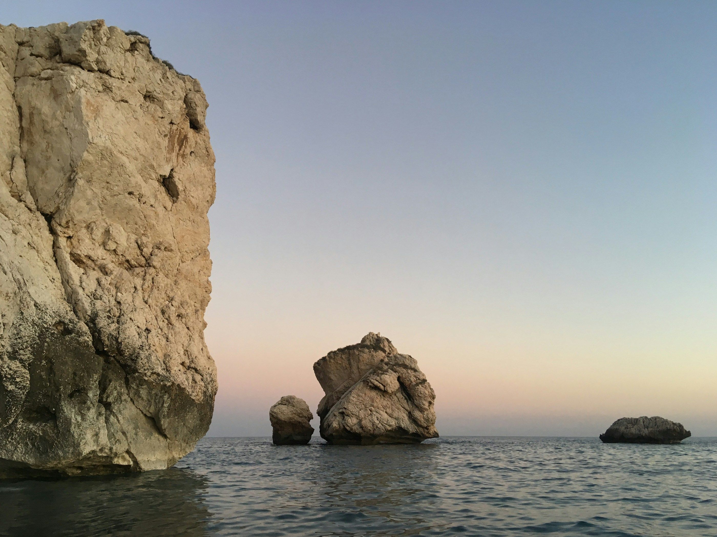 Petra tou Romiou, Aphrodite’s Rock, rising from a calm sea near Paphos at dusk.