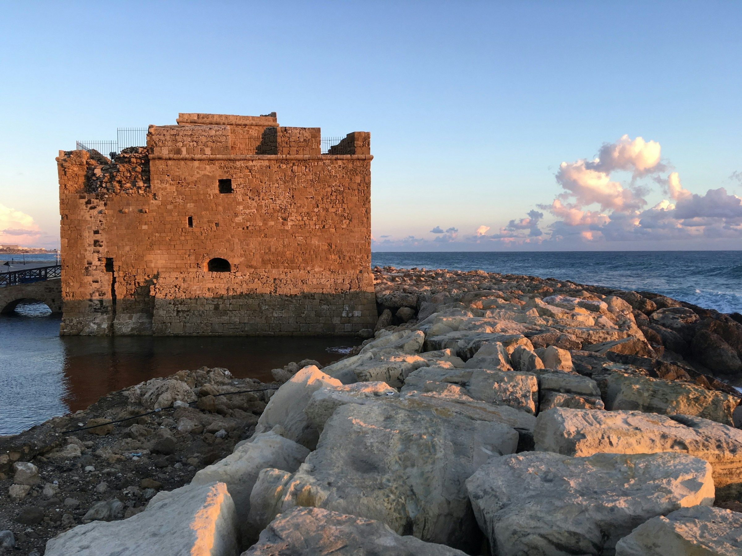 The medieval castle at Paphos harbour in warm evening light, with the sea behind it.